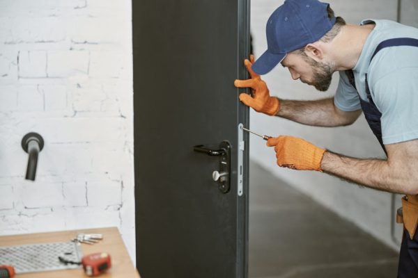 bearded-young-man-fixing-door-with-screwdriver-1
